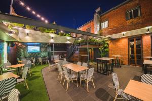 an outdoor patio with tables and chairs at night at Heritage Hotel Rockhampton in Rockhampton