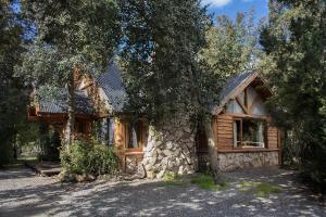 a log cabin with a tree in front of it at Patagonia Sin Fronteras in San Carlos de Bariloche