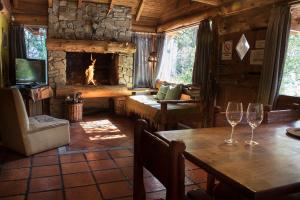 Patagonia Sin Fronteras في سان كارلوس دي باريلوتشي: غرفة معيشة مع موقد وطاولة مع كؤوس للنبيذ