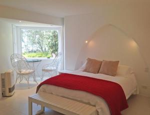 a bedroom with a bed with a red blanket and a window at Ohiwa Seascape Studios in Opotiki