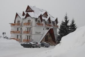 a large building with cars parked in the snow at Villa Milmari in Kopaonik