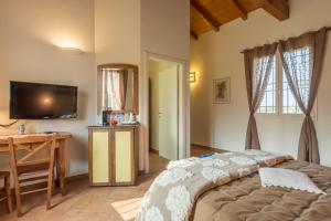 a bedroom with a bed and a desk and a television at Agriturismo Primaluna in Castenaso