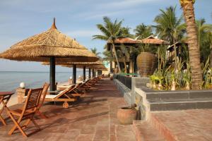 eine Reihe von Stühlen und Sonnenschirmen am Strand in der Unterkunft Lotus Village Resort in Mui Ne