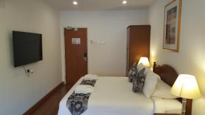 a bedroom with a bed and a flat screen tv at Heeren Straits Hotel in Malacca