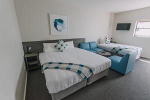 um quarto com 2 camas e uma cadeira azul em Studios On Beaumont em Newcastle