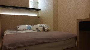 a bedroom with a bed with two pillows on it at Tanglin Mansion Apartment - Pakuwon Mall in Surabaya +14 photos