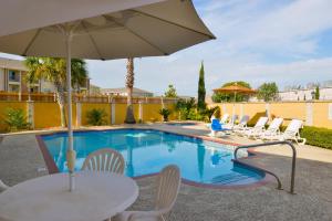una piscina con tavolo, sedie e ombrellone di Americas Best Value Inn & Suites Waller/Prairie View a Waller