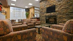 a waiting room with chairs and a fireplace at Best Western Plus Chateau Inn Sylvan Lake in Sylvan Lake