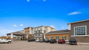 a parking lot with cars parked in front of buildings at Best Western Plus Lacombe Inn and Suites in Lacombe