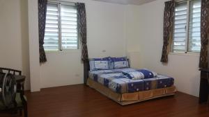 een slaapkamer met een bed in een kamer met ramen bij A-Ma Homestay in Fengli