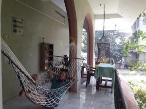 a boy laying in a hammock in a room at Rams Gratitude Inn in Varkala