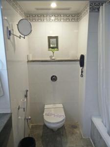 een kleine badkamer met een toilet en een spiegel bij Hotel Parisutham in Thanjāvūr