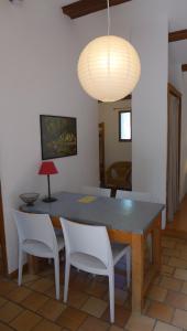a dining room table with two white chairs and a lamp at Gîte Marius in Mirabel-aux-Baronnies
