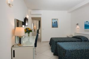 a hotel room with two beds and a table with a lamp at Hotel Weber Ambassador in Capri
