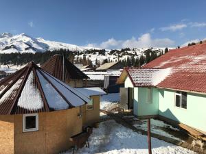 eine Gruppe von Gebäuden mit Schnee auf den Dächern in der Unterkunft Alakol-Jyrgalan Guest House in Dzhergalan