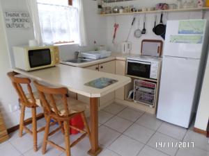 a kitchen with a table with a microwave and a refrigerator at Hermanus At Rikis Self Catering in Hermanus