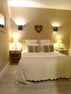 ein Schlafzimmer mit einem weißen Bett mit einem Herz an der Wand in der Unterkunft Cit'Hotel des Messageries in Saintes