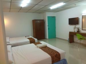 a hotel room with two beds and a television at Hotel K T Mutiara in Kuala Terengganu
