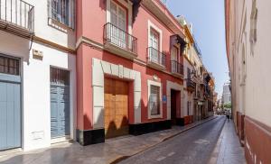 una calle vacía con un edificio rojo y blanco en Casa Palacio San Jose, en Sevilla