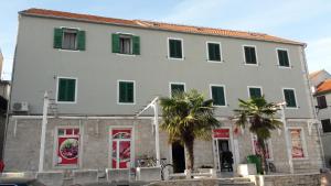 a large white building with green shutters and palm trees at Stars Palace Vodice in Vodice