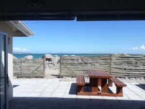 a wooden bench sitting on a patio with the ocean in the background at Beach House Bliss in Langebaan
