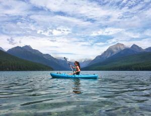 a woman is paddling a blue kayak on a lake at Buccaneer Motel in The Entrance