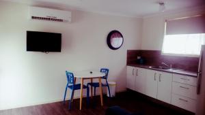 a kitchen with a table and two chairs and a tv at Silver Wattle Cabins in Mount Morgan
