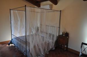 コルトーナにあるAgriturismo Dominus Domenicoのベッドルーム(白いカーテン付きの天蓋付きベッド1台付)