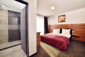 a hotel room with a bed and a walk in shower at Hotel President in Timişoara