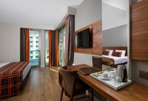 a hotel room with a desk with a laptop and a bed at Side Sunport Hotel - All Inclusive in Side +57 photos