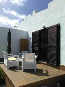 a patio with chairs and a table and a umbrella at Sun Luz Apartments 84 in Caleta De Fuste