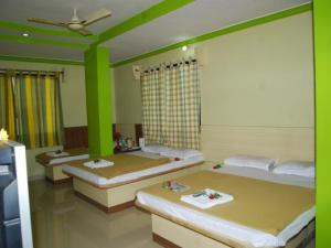 a room with three beds with green walls at Hotel Utsav in Shirdi