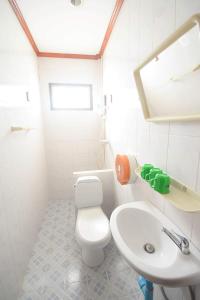 a white bathroom with a toilet and a sink at Intouch Guest House in Vientiane