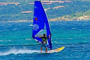 a man on a surfboard with a sail on the water at Hotel Porto Puddu - Il Nido dei Gabbiani in Porto Pollo