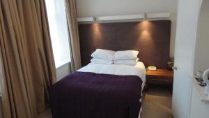 a hotel room with a bed with a large headboard at Sandyford Hotel in Glasgow