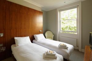 Dos camas en una habitación de hotel con velas en B&B Belgravia, en Londres