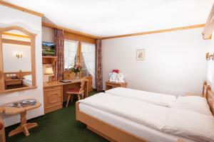 a bedroom with a bed and a desk and a table at Hotel Simmenhof in Lenk