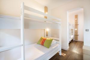 a white bunk bed in a white room with a green pillow at Hôtel Vacances Bleues Delcloy in Saint-Jean-Cap-Ferrat