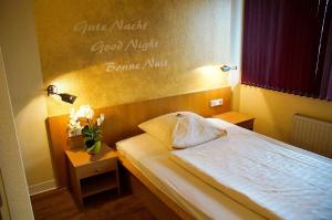 a bedroom with a bed with a sign on the wall at Hotel Alberga in Mettmann