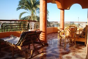 un balcone con sedie, tavolo e palma di Al Gezera Apartments a Luxor