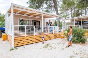 a family standing on the deck of a tiny house at Zaton Holiday Resort Mobile Homes in Nin