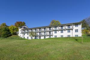 ein großes weißes Gebäude auf einem Grasfeld in der Unterkunft Hotel Irschenberg Süd in Irschenberg