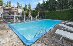 una gran piscina con sillas y una mesa en Mercure Paris Sud Les Ulis-Courtaboeuf, en Les Ulis