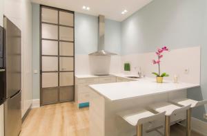 a kitchen with white counters and a sink and chairs at Luxury Alonso Martinez Madrid in Madrid