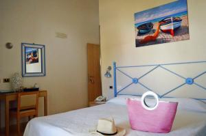 Un dormitorio con una cama con una bolsa rosa. en Hotel Mar & Sol, en Punta Secca