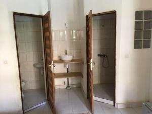 een badkamer met een wastafel en een douche met een spiegel bij Guesthouse Dalal ak Jàmm in Mbour