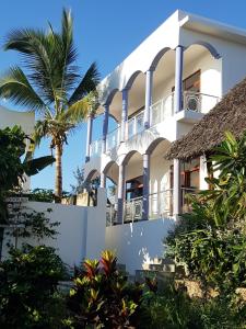 a building with a palm tree in front of it at Daeli Apartment in Kendwa