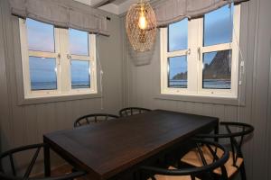 a dining room with a table and chairs and windows at Bleik Sea Cabins in Bleik