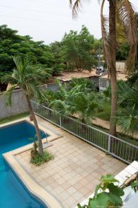 a fence next to a swimming pool with palm trees at B & B Le Nomade in Ouagadougou