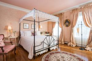 a bedroom with a canopy bed and a chair at Captain Farris House in South Yarmouth